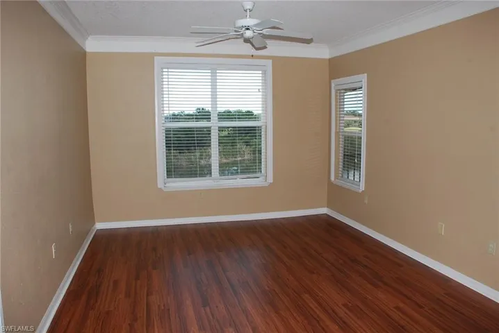 Spare room with ornamental molding, dark wood-type flooring, ceiling fan, and a textured ceiling