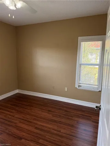 Empty room with ceiling fan, dark wood-style floors, and a textured ceiling
