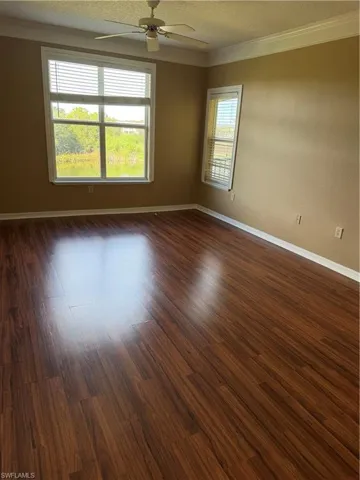 Spare room featuring crown molding, dark wood-style floors, ceiling fan, and a textured ceiling