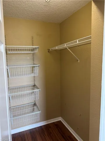 Walk in closet with dark wood-style flooring