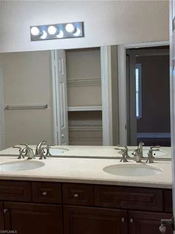 Full bathroom featuring double vanity and a closet