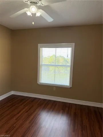 Spare room with a textured ceiling, a ceiling fan, and dark wood-style floors