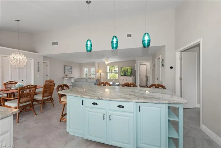 Kitchen featuring high vaulted ceiling, a kitchen bar, open shelves, a chandelier, and a kitchen island