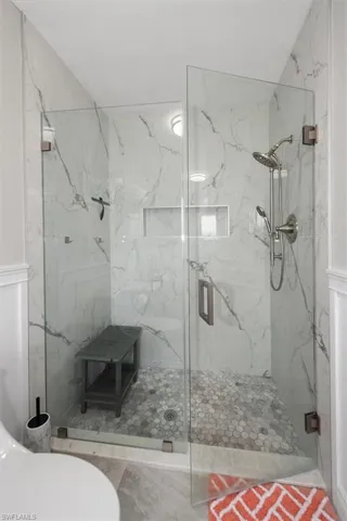 Bathroom with a marble finish shower and toilet
