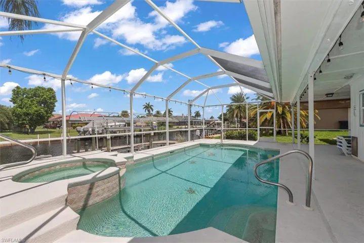 View of pool featuring a pool with connected hot tub, a water view, and boat lift