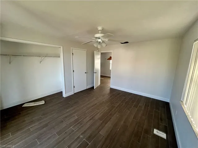 Unfurnished bedroom featuring dark hardwood / wood-style flooring and ceiling fan