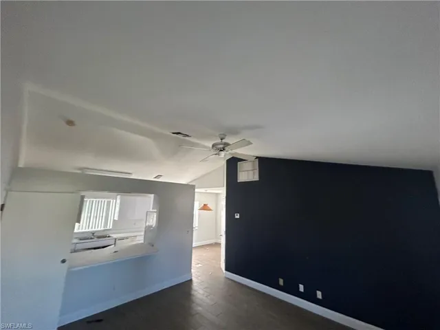 Spare room featuring lofted ceiling, dark hardwood / wood-style floors, and ceiling fan