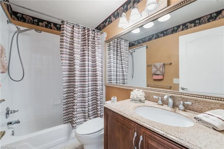 Bathroom featuring a vanity with granite-style countertop, integrated sink, and brushed nickel fixtures