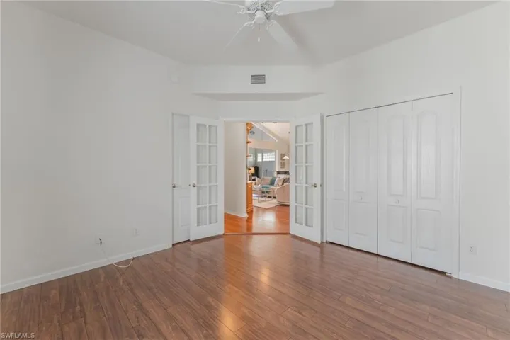 Room featuring wood-finish flooring, white walls, and a ceiling fan