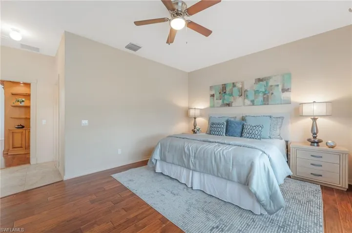 Spacious room featuring wood-finish flooring, a ceiling fan with integrated lighting, and neutral wall tones