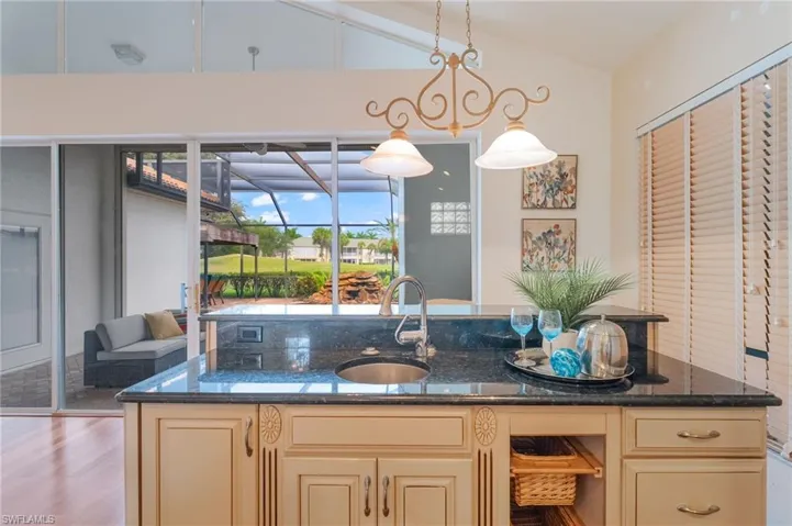 Kitchen island featuring a dark countertop with an integrated sink, cream-colored cabinetry, and built-in storage