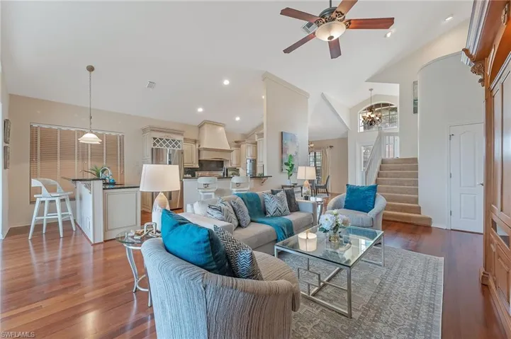 Open-concept living area featuring rich wood-finish flooring, vaulted ceilings, and a ceiling fan