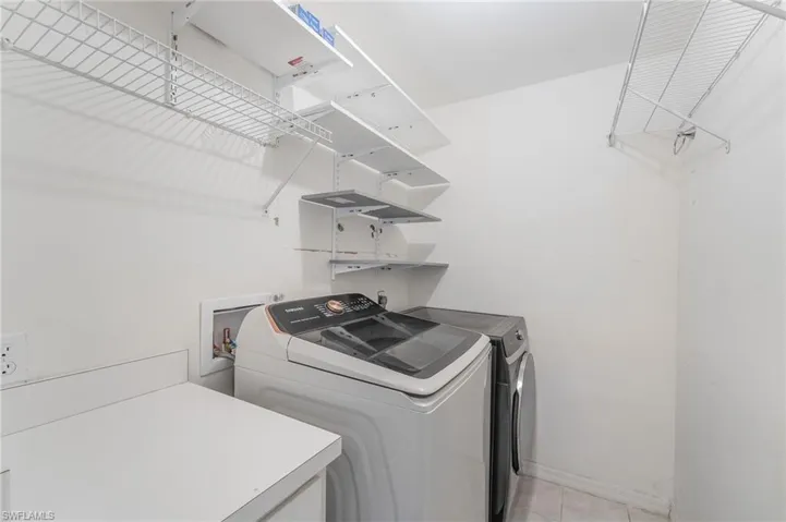 Dedicated laundry space featuring white wire shelving, wall-mounted adjustable shelving, and a white countertop for utility