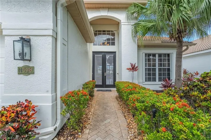 Stucco exterior featuring a paver walkway bordered by maintained shrubs and landscaping