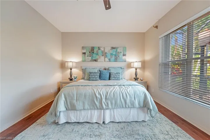 Spacious room featuring wood-finish flooring, a large window with horizontal blinds, and neutral wall tones