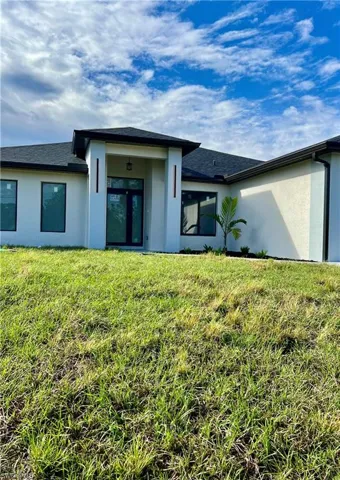 Rear view of house featuring stucco siding and a yard