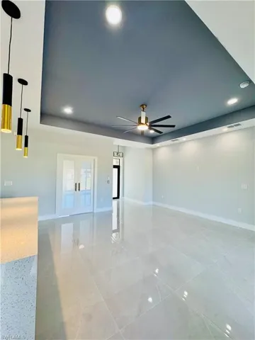 Spare room with a raised ceiling, recessed lighting, ceiling fan, and french doors