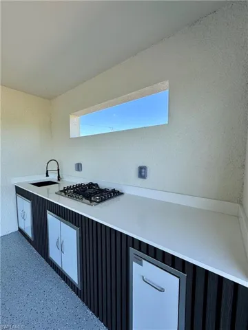 Kitchen featuring a textured wall, stainless steel gas stovetop, and light countertops