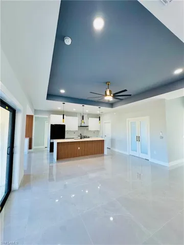 Unfurnished living room with recessed lighting, a tray ceiling, and ceiling fan