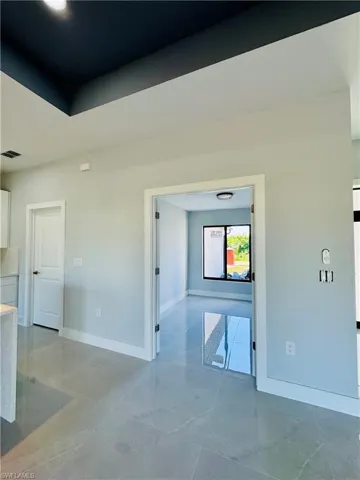 Empty room featuring a tray ceiling and light marble finish floors