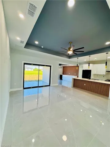 Unfurnished living room with recessed lighting, a tray ceiling, and a ceiling fan