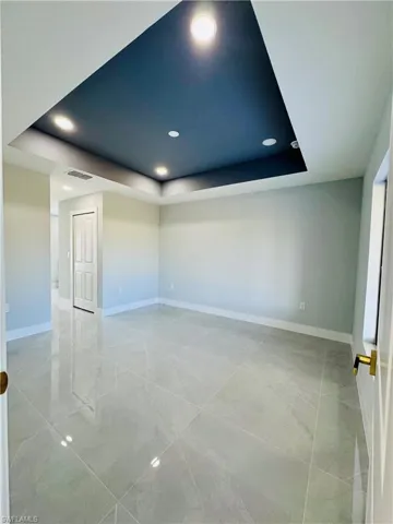 Empty room with a raised ceiling and recessed lighting