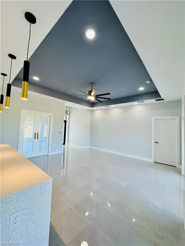 Spare room featuring a tray ceiling, a ceiling fan, recessed lighting, and french doors