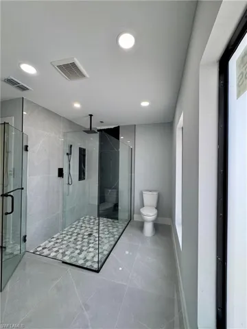 Bathroom featuring a stall shower, marble look tile flooring, and recessed lighting