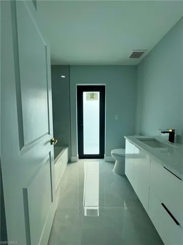 Full bathroom featuring vanity, a bath, and marble look tile flooring