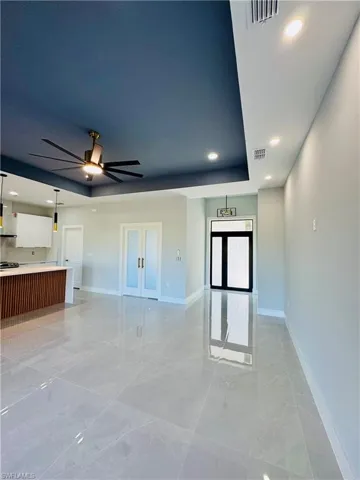 Unfurnished living room featuring recessed lighting, a raised ceiling, light marble finish flooring, and ceiling fan
