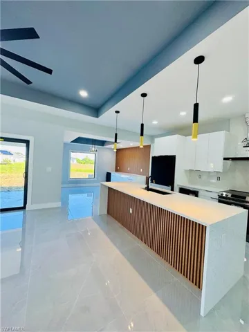 Kitchen featuring modern cabinets, white cabinetry, light countertops, a large island, and recessed lighting