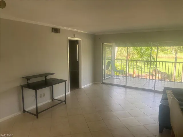 Empty room with ornamental molding and light tile patterned floors