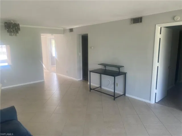 Empty room featuring ornamental molding and light tile patterned floors