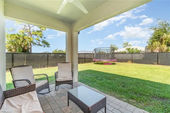 Fenced backyard featuring a patio area, a trampoline, and a ceiling fan