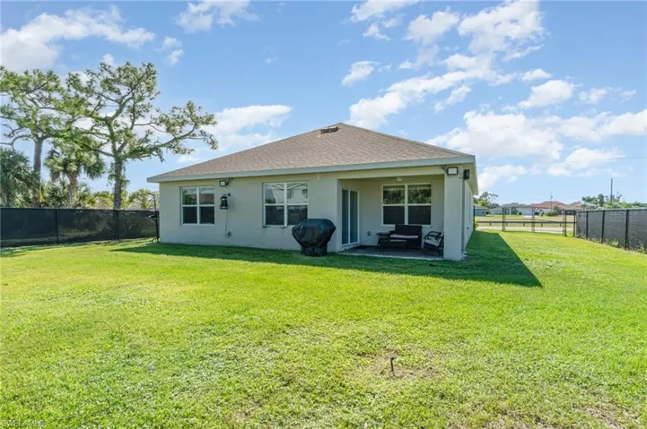 Rear view of house featuring a fenced backyard, stucco siding, a patio, and roof with shingles