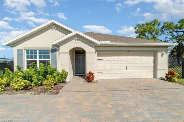 Single story home featuring decorative driveway, a garage, and stucco siding