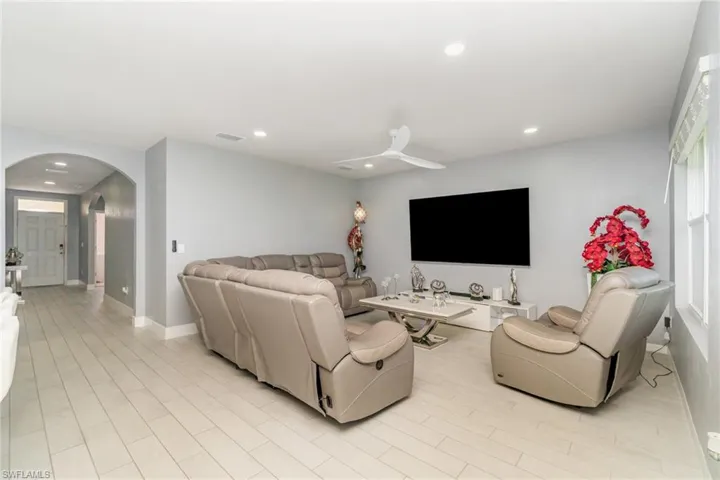 Living area featuring arched walkways, recessed lighting, ceiling fan, and light wood-style floors