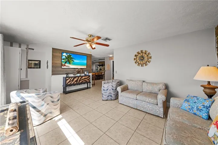 Living area with tile patterned flooring, a textured ceiling, and a ceiling fan