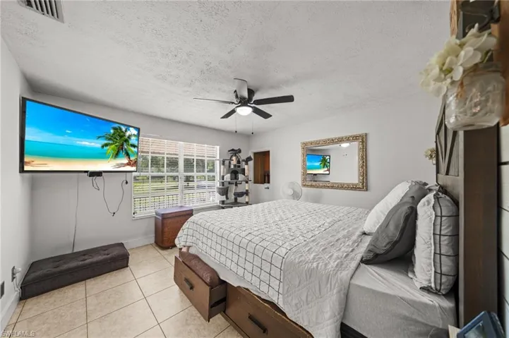 Bedroom featuring tile patterned floors, a textured ceiling, and ceiling fan