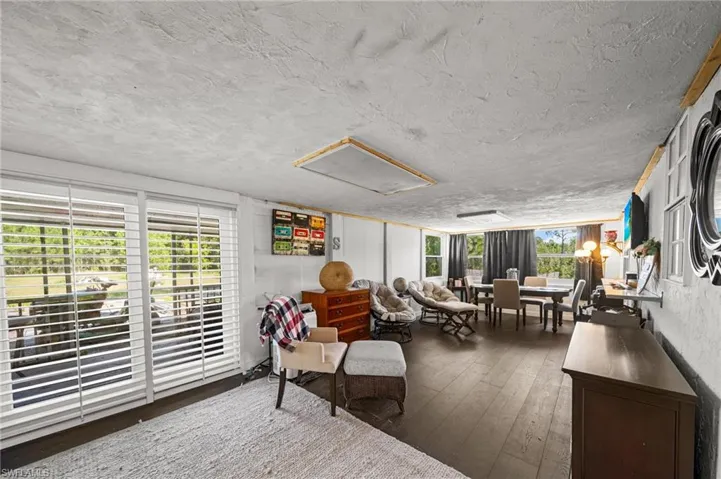 Living area featuring dark wood-style flooring and a textured ceiling