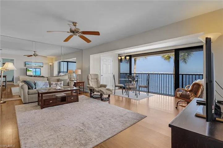 Living room featuring ceiling fan with notable chandelier and wood-type flooring
