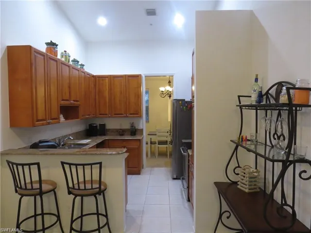 Kitchen featuring wood finish cabinets, a breakfast bar, a peninsula, light tile patterned floors, and a chandelier