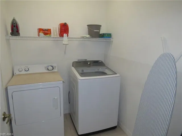 Laundry room with washing machine and clothes dryer and light tile patterned flooring
