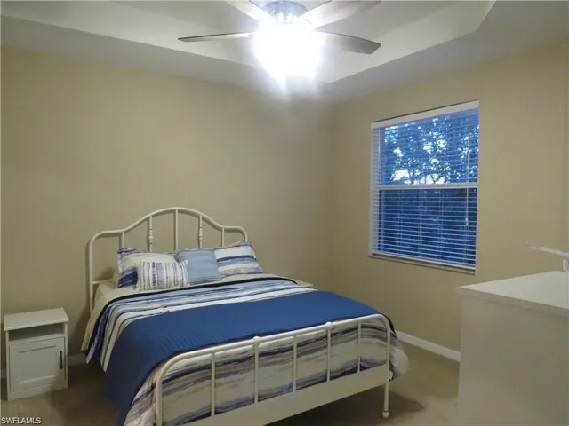 Bedroom with a ceiling fan and light colored carpet