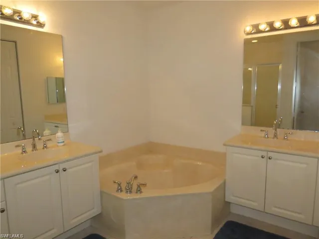 Bathroom with two vanities, a shower stall, and a bath