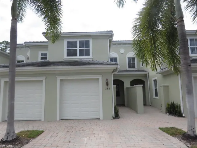 View of front facade with decorative driveway, stucco siding, and an attached garage
