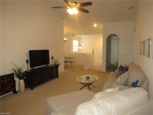 Living room with a ceiling fan, arched walkways, carpet flooring, lofted ceiling, and recessed lighting