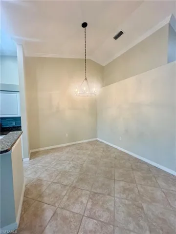 Unfurnished dining area featuring lofted ceiling and crown molding