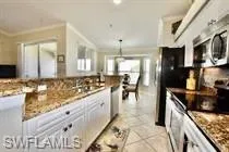 Kitchen featuring white cabinetry, stainless steel appliances, hanging light fixtures, and light tile patterned flooring