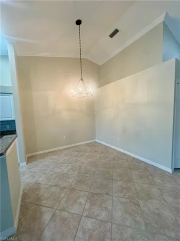 Unfurnished dining area featuring lofted ceiling and crown molding